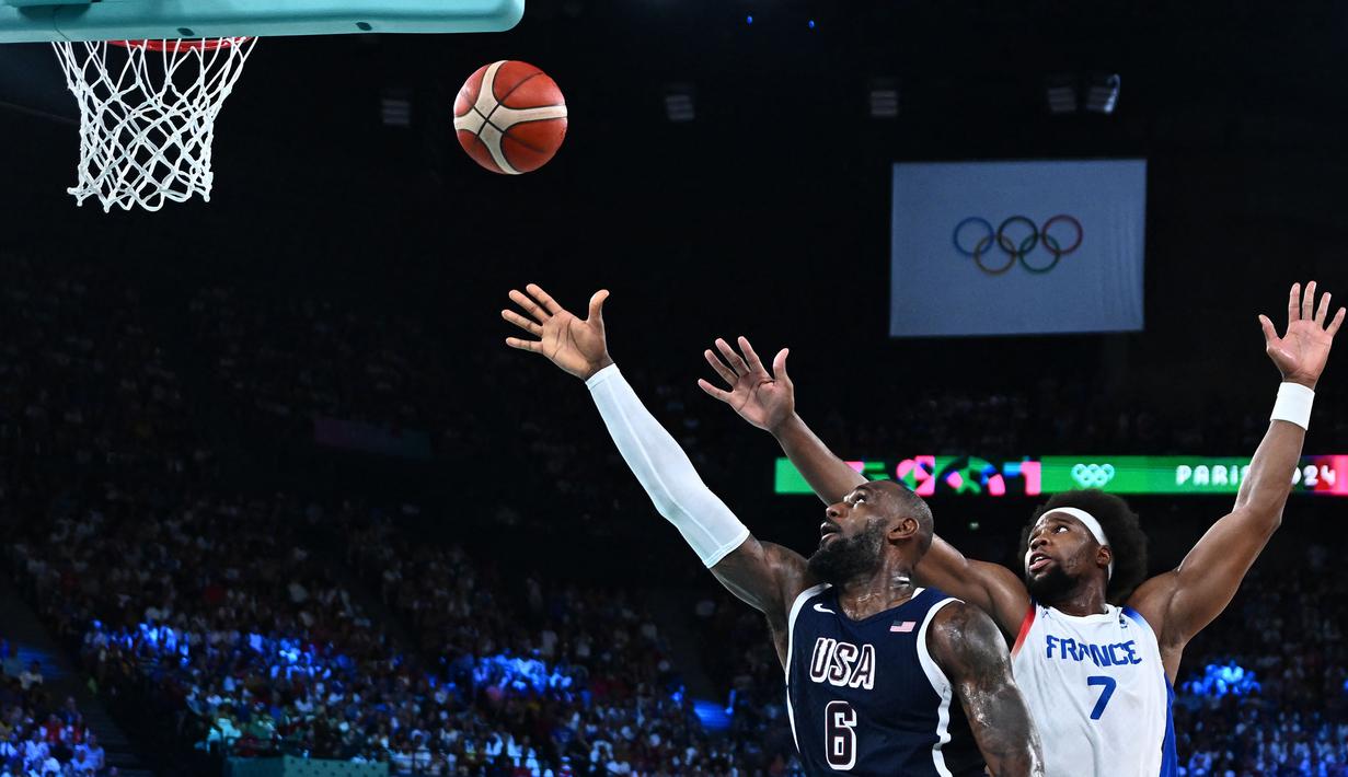 Pebasket Amerika Serikat, LeBron James (kiri) melakukan lay up dibayangi pebasket Prancis, Guerschon Yabusele pada pertandingan final Olimpiade Paris 2024 yang berlangsung di Bercy Arena, Paris, Prancis, Minggu (11/08/2024) dini hari WIB. (AFP/Aris Messinis)