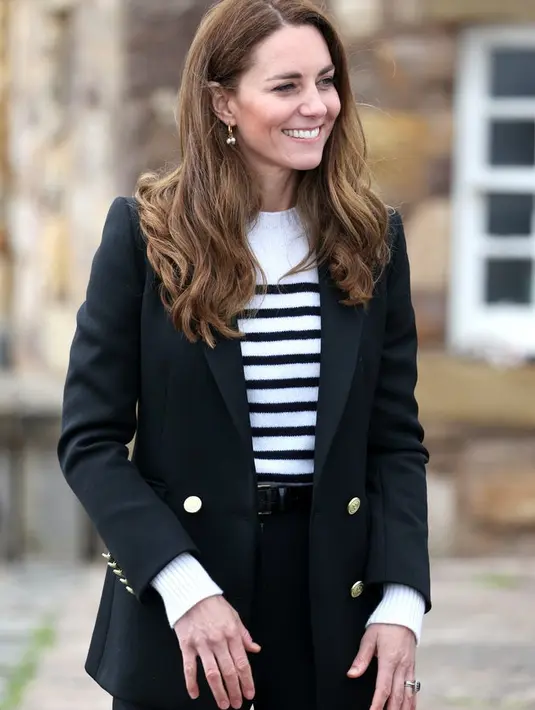 Kate Middleton tampil mengenakan sweater bergaris yang dirancang Erden, dipadu dengan blazer  model double-breasted dari Holand and Cooper, celana pixie berwarna hitam, dan sneakers kasual dari Veja. Foto: Bustle.