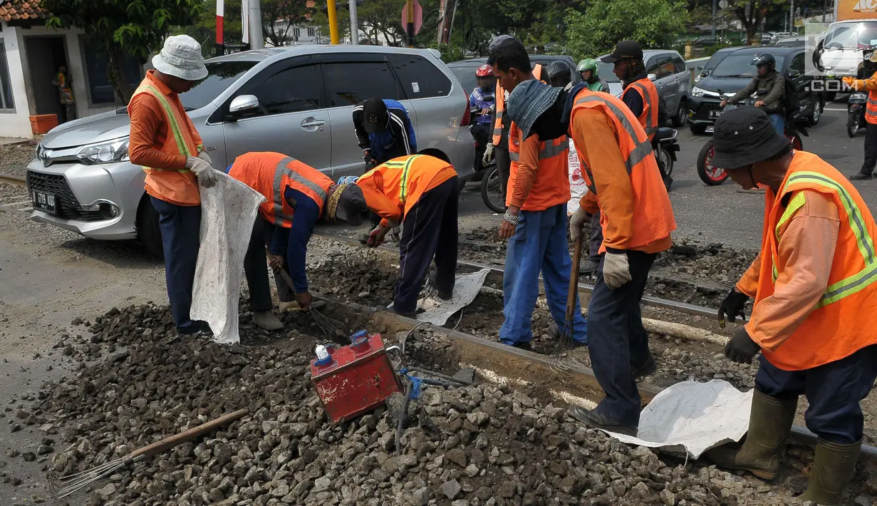 Sejumlah pengendara melitas di sebelah para pekerja yang sedang melakukan perawatan rutin rel kereta api di Manggarai, Jakarta, Selasa (11/7). Perawatan dan pengecekan tersebut guna menjamin keselamatan perjalanan kereta api. (Liputan6.com/Helmi Afandi)