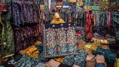 Seorang wanita menunjukkan selembar kain batik di ruang pamer di Sidoarjo, Jawa Timur, Sabtu (1/10/2022). Indonesia akan memperingati Hari Batik Nasional pada 2 Oktober. (JUNI KRISWANTO/AFP)