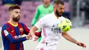 Bek Barcelona, Gerard Pique dan penyerang Real Madrid, Karim Benzema berbeut bola  pada laga La Liga bertajuk El Clasico di Nou Camp, Sabtu (24/10/2020). Barcelona harus menelan pil pahit kalah 1-3 dari musuh bebuyutannya Real Madrid di kandang sendiri, Nou Camp. (AP Photo/Joan Monfort)