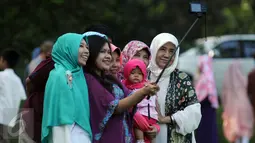Warga berfoto keluarga secara selfie usai melaksanakan Salat Idul Fitri 1437 H di Kebun Raya Bogor, Rabu (6/7). Pemerintah Kota Bogor menyelenggarakan Salat Idul Fitri 1437 H yang dipusatkan di areal Kebun Raya. (Liputan6.com/Helmi Fithriansyah)