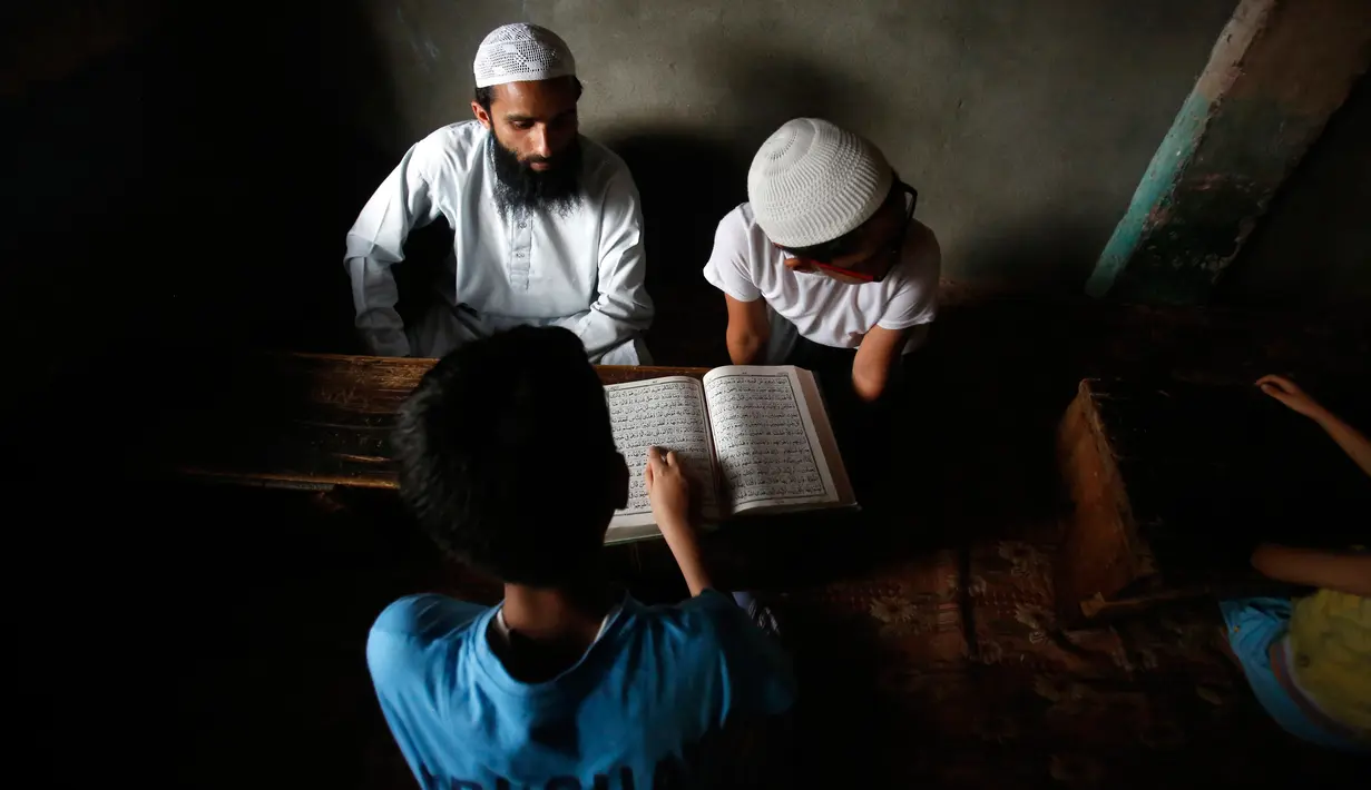 Seorang anak serius membaca Al-Quran saat di sebuah madrasah lokal selama bulan Ramadan di Srinagar, Kashmir yang dikuasai India, (30/5). Di bulan puasa umat muslim menahan diri untuk tidak makan dan minum. (AP Photo / Mukhtar Khan)