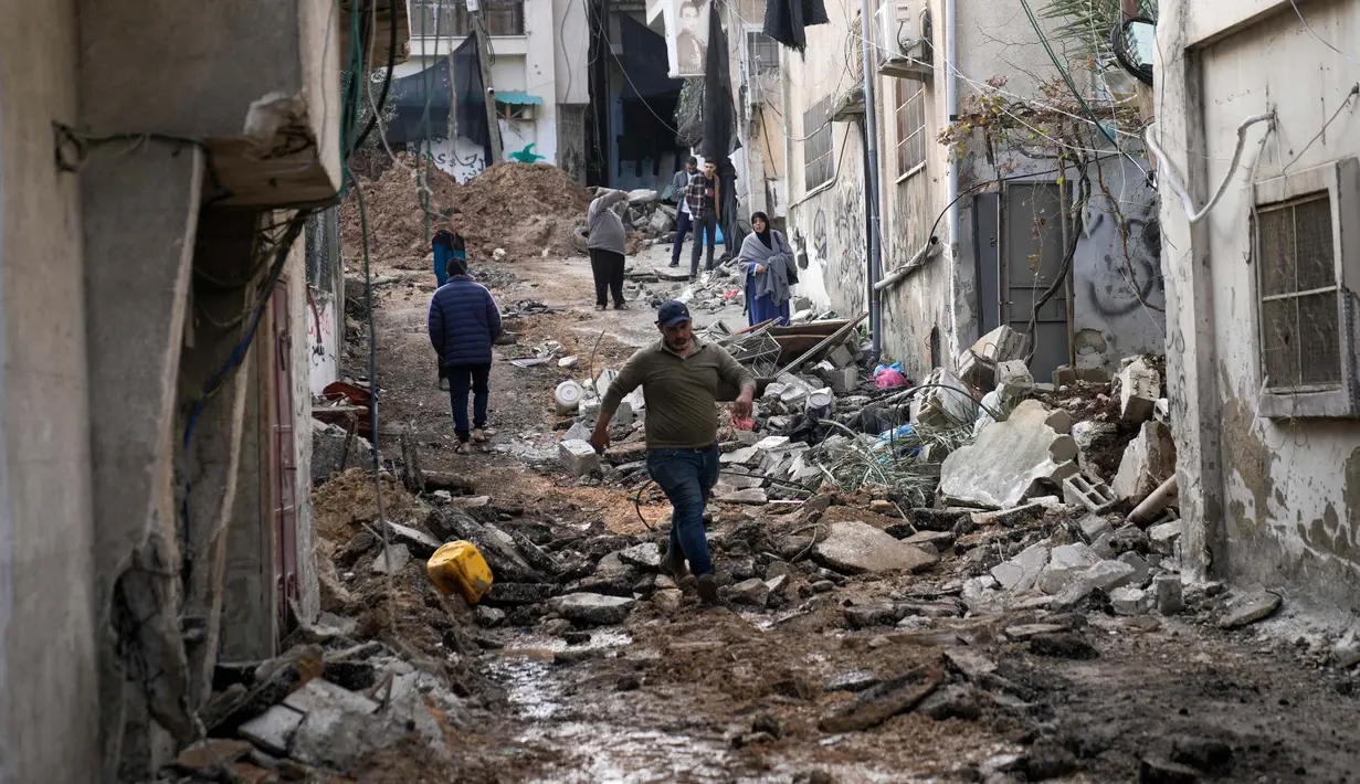 Warga Palestina berjalan setelah penyerbuan militer Israel ke kamp pengungsi Nur Shams di Tepi Barat, Rabu 27 Desember 2023. (AP Photo/Majdi Mohammed)