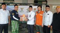 Kepala Kemenag Garut Cece Hidayat, bersama Ketua Baznas Garut Abdullah Effendy, secara simbolis memberikan fasilitas amplifier toa yang diberikan kepada pengurus masjid At-Thohirin di kawasan blok terdampak banjir Cimacan. (Liputan6.com/Jayadi Supriadin)