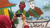 Warga mengambil gambar mural bertema budaya Betawi di kawasan Kampung Sentra Kreatif, RW 006 Kota Bambu Selatan, Jakarta, Rabu (3/11/2021). Pengembangan kawasan ini juga untuk memberdayakan potensi perekonomian masyarakat, baik kuliner, jasa, dan tanaman obat. (Liputan6.com/Herman Zakharia)