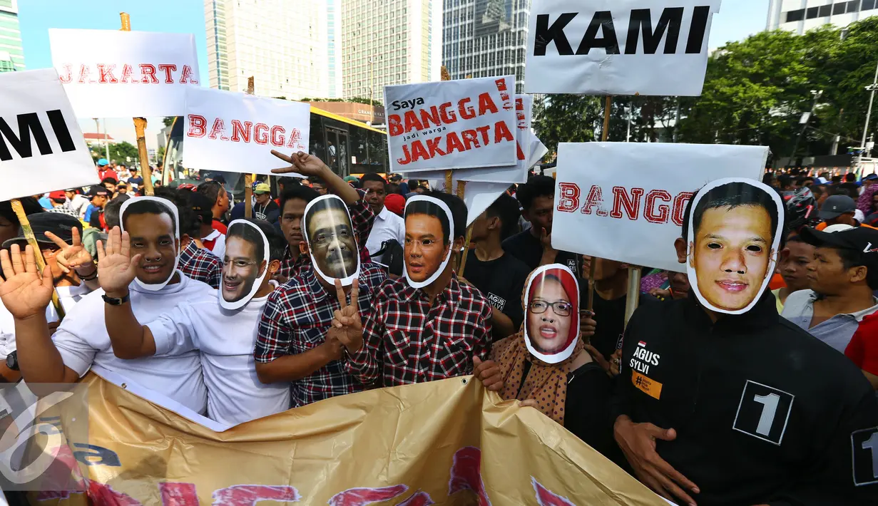 Para relawan berfoto bersama mengenakan topeng dan atribut tiga paslon Cagub/Cawagub DKI Jakarta saat melakukan aksi kampanye pilkada damai, aman dan sportif di CFD, kawasan Bunderan HI, Jakarta, Minggu (30/10). (Liputan6.com/Johan Tallo)