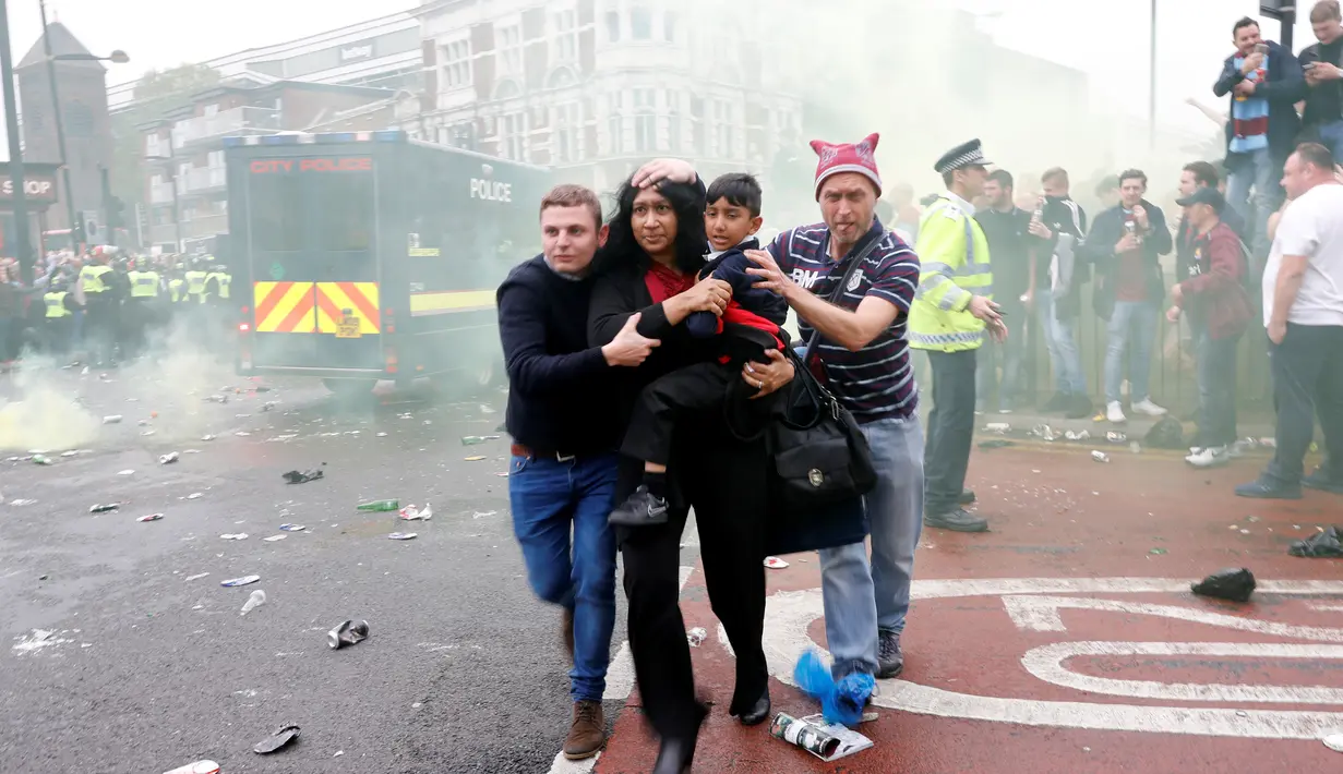 Sejumlah orang menyelamatkan diri ketika kericuhan di depan Stadion Boleyn Ground, London, Selasa (10/5). Kedatangan bus skuat Manchester United disambut dengan lemparan botol dari ratusan suporter West Ham. (Reuters/Eddie Keogh)