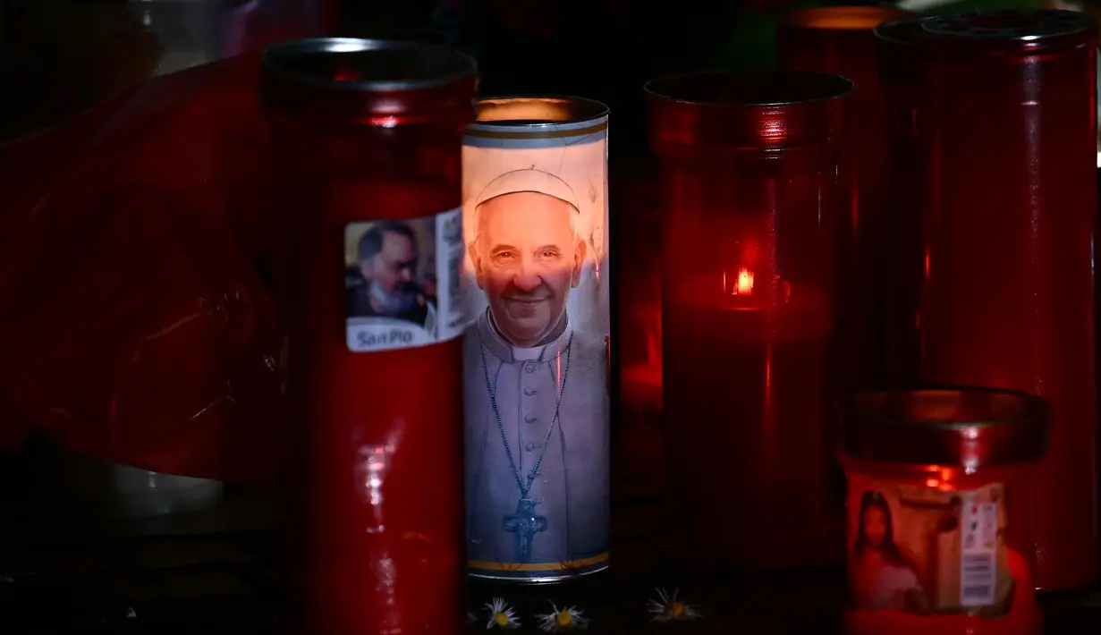 Lilin diletakkan di patung Yohanes Paulus II di luar Rumah Sakit Universitas Gemelli di mana Paus Fransiskus dirawat di rumah sakit karena pneumonia, di Roma pada tanggal 3 Maret 2025. (Filippo MONTEFORTE/AFP)