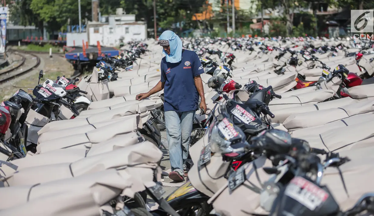 Pekerja melewati motor pemudik sebelum dikirim dengan kereta api di Stasiun Jakarta Gudang, Selasa (28/5/2019). Direktorat Lalu Lintas dan Angkutan Kereta Api Kementerian Perhubungan mengangkut 18.096 motor pemudik secara gratis pada mudik Lebaran 2019. (Liputan6.com/Faizal Fanani)