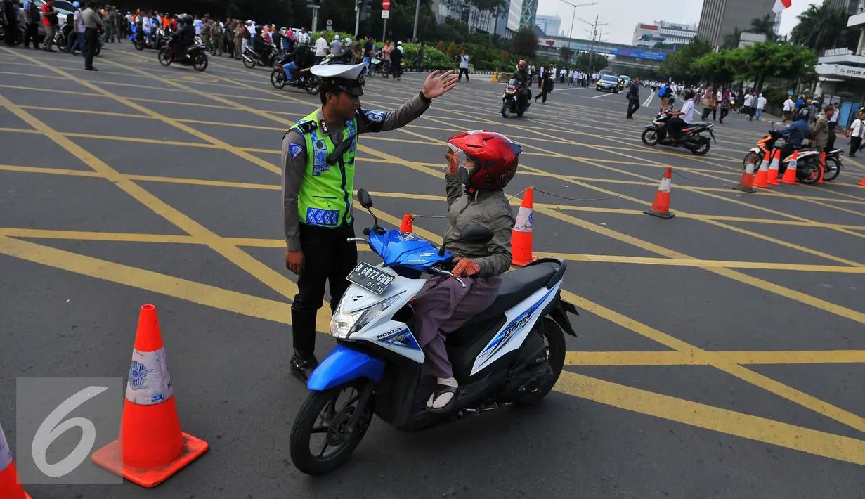 Petugas memberi petunjuk kepada pengendara motor saat pengalihan arus di kawasan Sarinah, Jakarta, Jumat (4/11). Pengalihan arus lalu lintas ini disebabkan karena beberapa titik jalan tidak bisa digunakan akibat aksi massa. (Liputan6.com/Angga Yuniar)