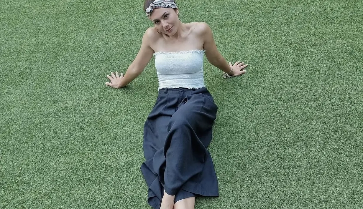 Atau atasan tanpa tali berwarna putih polos kali ini dipadunya dengan celana panjang yang flowy berwarna biru navy. [Foto: Instagram/wulanguritno]