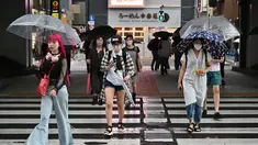 Orang-orang menyeberang di bawah rel kereta api selama hujan yang terisolasi di distrik Akihabara Tokyo (13/8/2022). Hujan lebat yang dibawa oleh Badai Tropis Meari melanda daerah tersebut. (AFP/ Richard A. Brooks)
