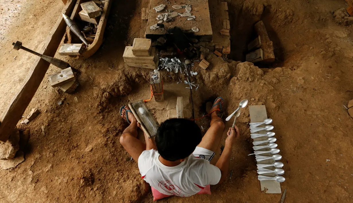 Seorang pria membuat sendok dengan melelehkan bese bom yang dijatuhkan oleh pesawat Angkatan Udara AS selama Perang Vietnam, di  Desa Ban Napia, Provinsi Xieng Khouang, Laos (03/9). (REUTERS/Jorge Silva)