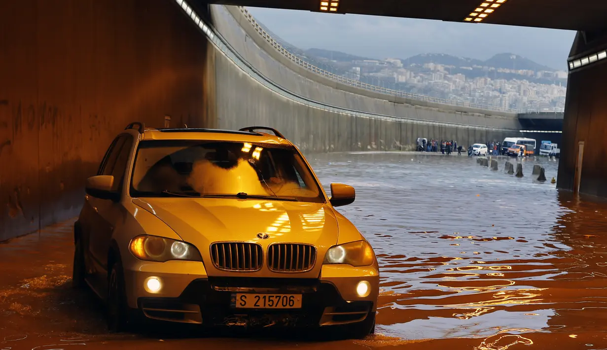 Pengendara mobil berusaha melintasi terowongan yang banjir di pinggiran selatan Beirut Ouzai, Lebanon (9/12/2019). Hujan deras membuat sejumlah rumah dan kendaraan di Lebanon terendam banjir dan melumpuhkan daerah-daerah dari ibukota Beirut, Lebanon. (AP Photo/Bilal Hussein)