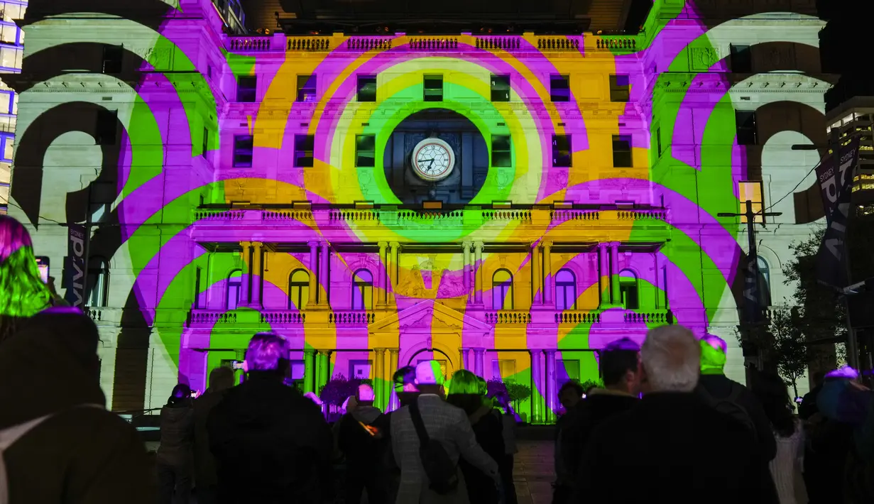 Pengunjung kawasan pusat bisnis Sydney menyaksikan cahaya yang merupakan bagian dari festival tahunan Vivid di sebuah gedung, Senin, 29 Mei 2023. (AP Photo/Mark Baker)