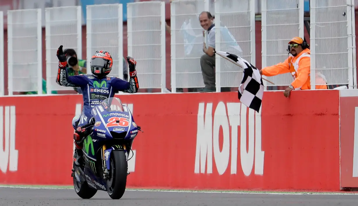 Pembalap Movistar Yamaha, Maverick Vinales melakukan selebrasi di atas motornya setelah finis pertama pada balapan MotoGP Argentina di Sirkuit Termas de Rio Hondo, Minggu (9/4). (AP Photo/Nicolas Aguilera)