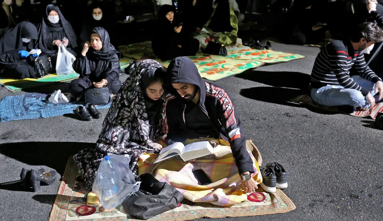 Warga Iran yang sebagian mengenakan masker menghadiri acara kajian dan pengajian Lailatul Qadar, salah satu malam paling suci selama bulan Ramadan, di luar masjid di Teheran, Rabu (13/5/2020). Pemerintah Iran membuka kembali masjid-masjid untuk manyambut malam Lailatul Qadar. (ATTA KENARE/AFP)