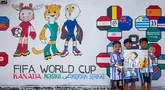 Anak-anak berpose di depan mural yang menampilkan turnamen sepak bola Piala Dunia 2026 di Polewali Mandar, Sulawesi Barat, Kamis 11 Juni 2026. (Muhammad SALIM/AFP)