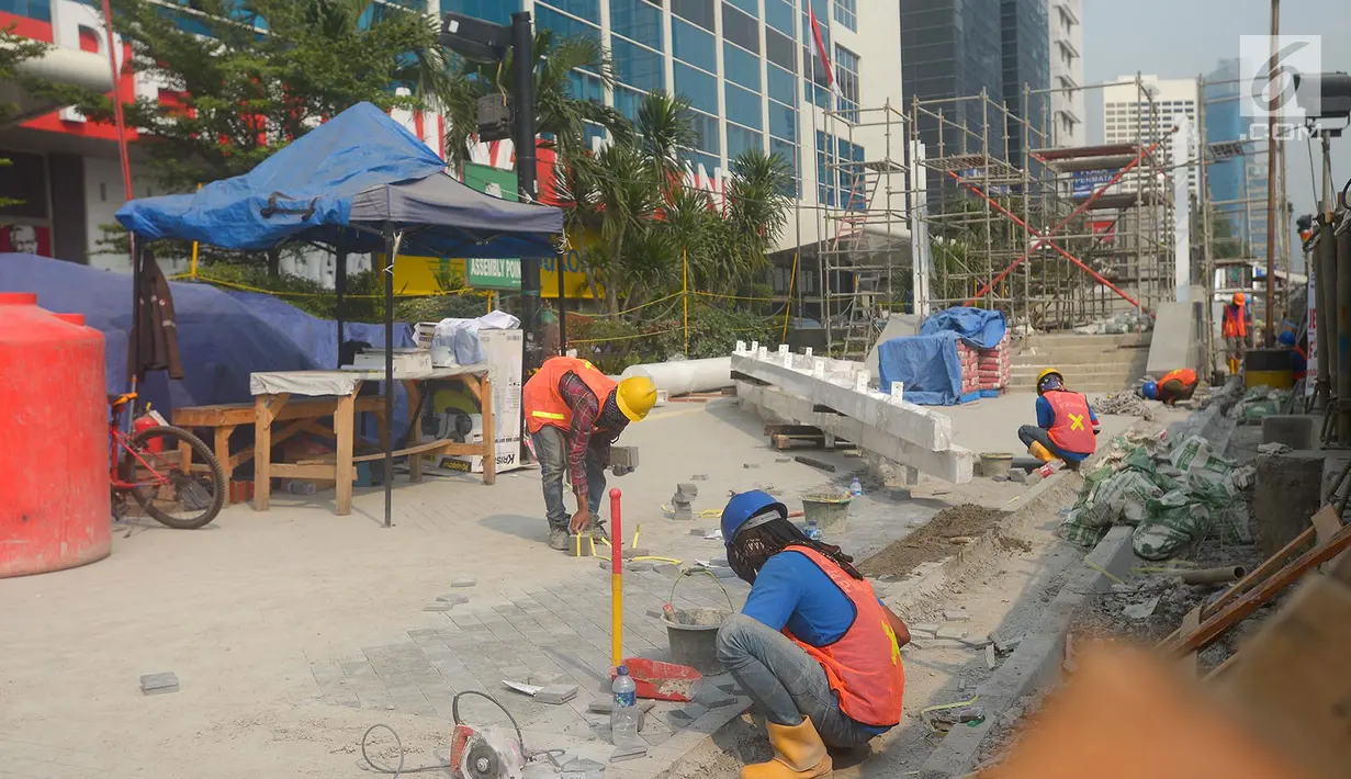 Pekerja menyelesaikan proyek pembangunan trotoar di Jalan MH Thamrin,Jakarta,Kamis (19/7). Jelang Asian Games 2018, pengerjaan infrastruktur di Jakarta terus dikebut. (Merdeka.com/Imam Buhori)