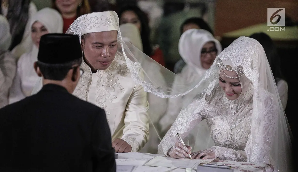 Angel Lelga menandatangi berkas saat akad nikah dengan Vicky Prasetyo di Mesjid Istiqlal, Jakarta, Jumat (9/2). Sebelum mengucapkan ijab kabul, Vicky Prasetyo membaca Al Quran surat Ar Rahman dengan tartil. (Liputan6.com/Faizal Fanani)