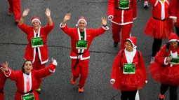 Peserta berkostum Sinterklas melambaikan tangan saat mengikuti Santa Claus Run di Madrid, Spanyol, Minggu (9/12). Ribuan orang berjalan dan berlari dalam perlombaan Santa tahunan melintasi jalan-jalan ibu kota Spanyol. (Gabriel BOUYS / AFP)