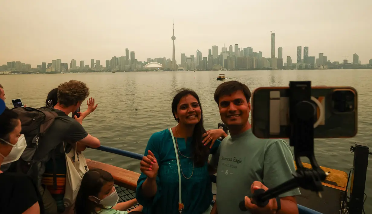 Wisatawan menaiki feri dari Kepulauan Toronto menuju pusat kota saat asap akibat kebakaran hutan di Ontario Utara menyelimuti Toronto dan menyebabkan kualitas udara memburuk, di Toronto, Ontario, Kamis, 15 Juli 2026. (AFP/ Cole Burston)