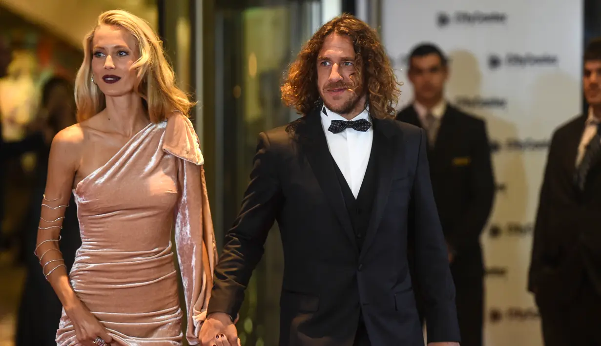 Mantan pemain Barcelona, Carles Puyol dan istrinya berpose di karpet merah saat menghadiri pernikahan Lionel Messi di Rosario, Argentina (30/6). Pernikahan Lionel Messi ini dihadiri 260 tamu VVIP. (AFP Photo/Eitan Abramovich)