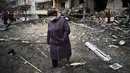 Seorang wanita berjalan di depan bangunan yang rusak setelah peluru militer Rusia menghantam di Koshytsa Street, Kiev, Ukraina (25/2/2022). Ledakan di Kiev memicu kekerasan setelah Presiden Rusia Vladimir Putin menentang peringatan Barat untuk melancarkan invasi darat skala penuh. (AFP/Daniel Leal)