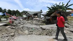 Seorang pria berjalan melewati jalan rusak usai gempa dan tsunami melanda Kabupaten Sigi, Sulawesi Tengah, Kamis (4/10). BNPB mengatakan ada empat kecamatan sulit dijangkau petugas usai gempa dan tsunami melanda daerah tersebut. (ADEK BERRY/AFP)