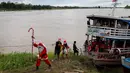 Untuk informasi, sudah sejak tahun 1998 kelompok relawan Sahabat Sinterklas ini berbagi kebahagiaan Natal untuk anak-anak di komunitas pedesaan dan tepi sungai di hutan hujan Amazon. Tampak dalam foto, relawan Jorge Alberto Barrozo, yang mengenakan kostum Sinterklas, berjalan untuk mengantarkan hadiah kepada anak-anak di komunitas tepi sungai di daerah pedesaan Careiro da Varzea, negara bagian Amazonas, Brasil pada Sabtu 20 Desember 2025. (Michael DANTAS/AFP)