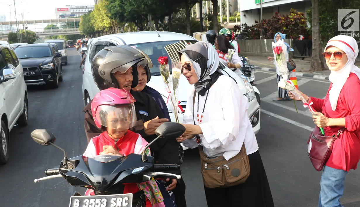 Relawan Jokowi saat membagikan bunga mawar kepada pengendara motor di Kawasan Sarinah, Jakarta, Minggu (29/9/2019). Aksi bagi bunga tersebut merupakan aksi damai kami bersama Jokowi. (Liputan6.com/Angga Yuniar)