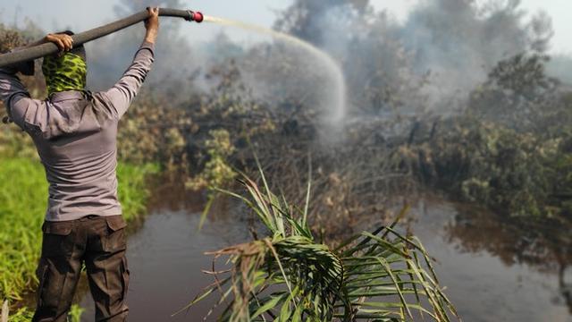 Polisi menyemprotkan air ke kebakaran lahan agar apinya tak meluas dan menimbulkan bencana kabut asap.