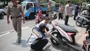 Petugas Dishub DKI menggembosi ban sepeda motor yang nekat parkir liar di trotoar sepanjang Jalan Kramat Raya, Senen, Jakarta, Jumat (22/9). Razia dilakukan untuk mengembalikan fungsi trotoar sebagai jalur pedestrian. (Liputan6.com/Faizal Fanani)