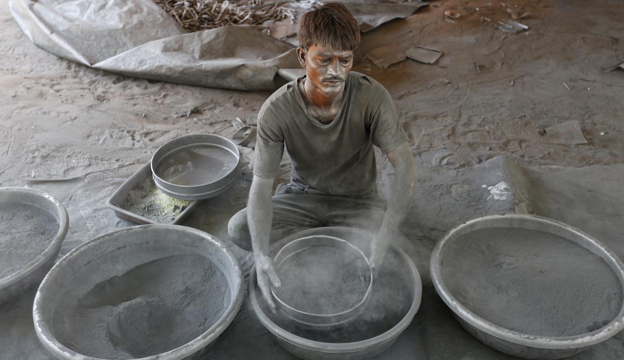 Seorang pekerja menyaring bubuk mesiu untuk membuat petasan, di sebuah pabrik pinggiran  Ahmadabad, Senin (22/10). Permintaan petasan di India semakin meningkat jelang perayaan Festival "Cahaya" Diwali bagi umat Hindu. (AP/Ajit Solanki)