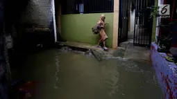 Seorang anak melintasi banjir di permukiman Jati Padang, Jakarta, Kamis (30/11). Banjir yang terjadi tersebut akibat tanggul darurat di Kali Pulo jebol karena genangan air yang cukup deras dan membanjiri Permukiman Sekitar. (Liputan6.com/Johan Tallo)