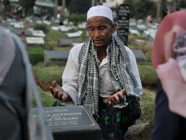 Seorang pria bernama Muhammad Hoir memimpin doa 'Talkin' untuk peziarah di Tempat Pemakaman Umum (TPU) Kemiri, Rawamangun, Jakarta, Selasa (15/5). (Merdeka.com/Iqbal S Nugroho)