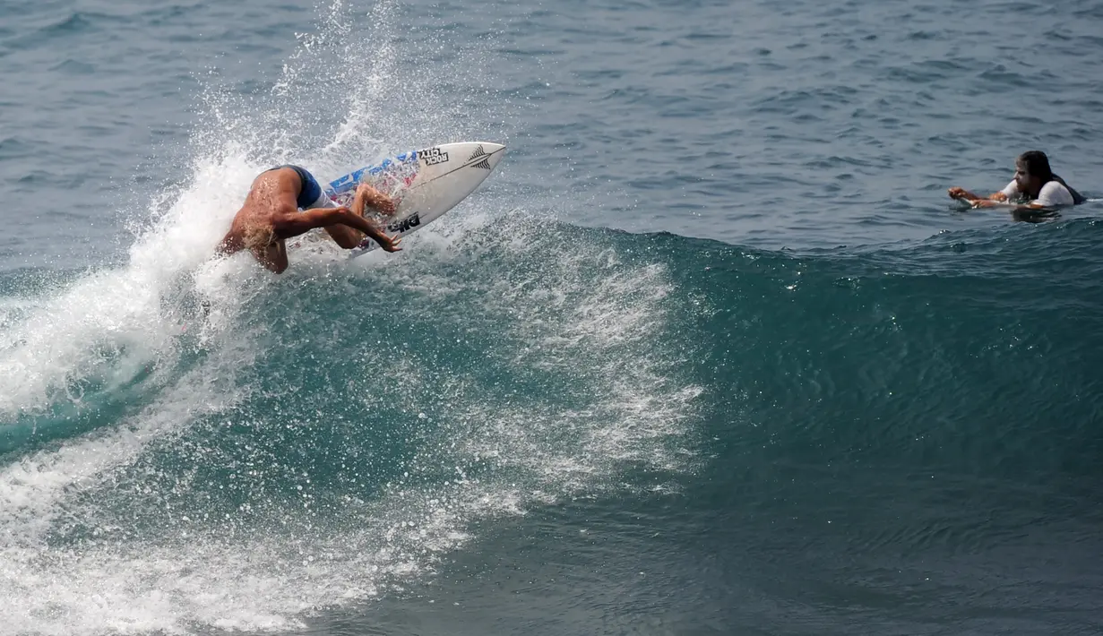 Turis beraksi di atas ombak saat bermain selancar di pantai Uluwatu Kuta Selatan di Kabupaten Badung, Bali pada 20 Desember 2018. Di Bali, terdapat banyak pantai yang merupakan lokasi ideal untuk kegiatan berselancar. (Photo by SONNY TUMBELAKA / AFP)