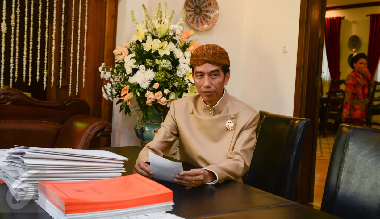 Mengenakan baju adat dan belangkon, Presiden Jokowi menandatangani sejumlah dokumen di sela rangkaian acara pernikahan putranya Gibran Rakabuming Raka-Selvi Ananda, di kediamannya, di Solo, Jawa Tengah, Rabu (10/6/2015). (Liputan6.com/Faizal Fanani)