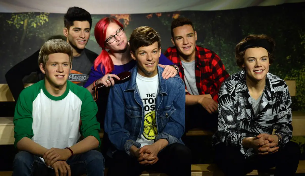 Seorang pegawai tampak berpose bersama patung boyband asal Inggris tersebut di museum lilin Madame Tussauds, London, Rabu (6/8/14). (AFP PHOTO/Carl COURT)