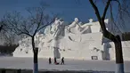 Orang-orang berjalan di samping patung salju raksasa di Pameran Seni Patung Salju Internasional Harbin Sun Island menjelang Festival Es dan Salju Internasional Harbin Tiongkok ke-39 di Harbin, di provinsi Heilongjiang timur laut China (4/1/2023). (AFP/Hector Retamal)