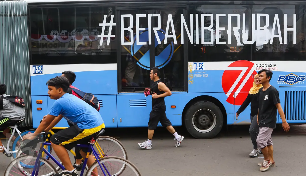 Sebuah bus TransJakarta koridor 1 dengan stiker tag #Berani Berubah melintas ketika masyarakat Jakarta berolahraga saat Car Free Day (CFD) di kawasan Bundaran HI, Jakarta, (14/08). (Liputan6.com/Fery Pradolo).