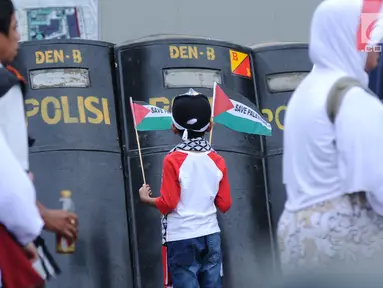 Seorang anak melihat tameng polisi saat mengikuti aksi dukungan bagi negara Palestina di depan Kedubes AS, Jakarta, Minggu (10/12). Mereka memprotes keputusan Presiden Trump yang mengakui Yerusalem jadi Ibu Kota Israel. (Liputan6.com/Helmi Fithriansyah)