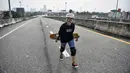 Longboarder dan penderita kanker Nongluck Chairuettichai, juga dikenal sebagai Jeab, berjalan di jalan raya yang belum selesai selama sesi latihan di Bangkok pada 9 September 2020. Kegiatan ini dilakukan sebagai jalan pemulihan dari kanker payudara yang dideritanya. (Lillian SUWANRUMPHA/AFP)