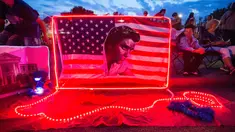 Bendera Amerika dengan wajah Elvis Presley terpajang di depan bekas rumah Elvis di Graceland, Memphis, Tennessee, Selasa (15/8). Para penggemar menghadiri peringatan 40 tahun kematian bintang rock n roll tersebut. (AP Photo/Brandon Dill)