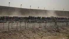 Migran berbaris antara penghalang kawat berduri dan pagar perbatasan di perbatasan AS-Meksiko, seperti yang terlihat dari Ciudad Juarez, Meksiko, Selasa (9/5/2023). (AP Photo/Christian Chavez)