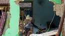 Seorang wanita membersihkan puing-puing dari rumahnya di desa Carita, Indonesia yang dilanda tsunami, Banten, Kamis, (27/12). Pemerintah telah memperluas zona larangan di sekitar pulau gunung berapi pulau yang memicu tsunami. (AP Photo/Achmad Ibrahim)
