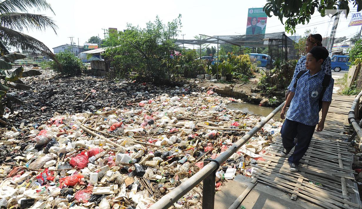 Dua pelajar melewati jembatan bambu di atas Sungai Kalibaru yang sudah menjadi tumpukan sampah di Kampung Bambu Kuning, Bojong Baru, Bogor (12/9). (Merdeka.com/Arie Basuki)