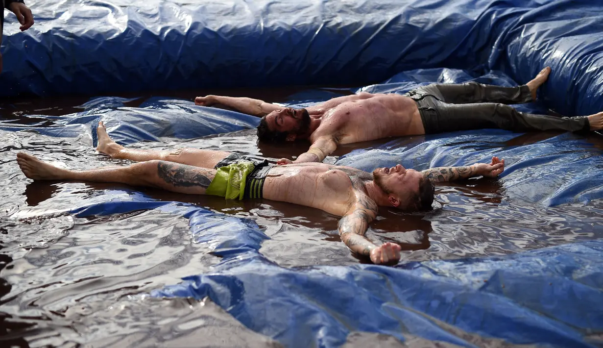 Pegulat terkapar saat mengikuti World Gravy Wrestling Championships ke-10 di Rose 'n' Bowl Pub di Inggris (28/8). Pertandingan gulat ini cukup unik, karena digelar di sebuah kolam selam dua menit. (AFP Photo/Oli Scarff)