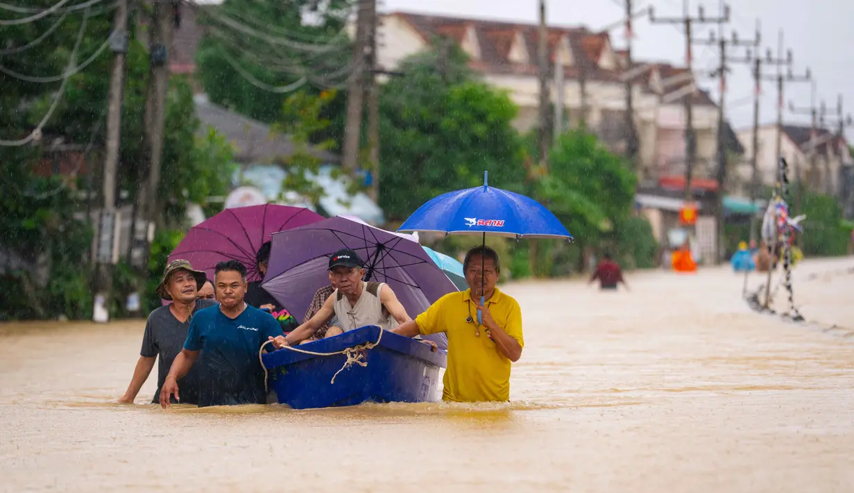 Ketinggian air di sejumlah distrik dilaporkan mencapai dua meter. Tampak dalam foto, warga berjalan melewati banjir sementara warga dievakuasi dengan perahu di Hat Yai, Provinsi Songkhla, Thailand selatan, pada Selasa 25 November 2025. (Arnun Chonmahatrakool/THAI NEWS PIX/AFP)